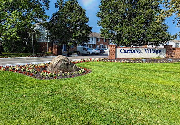 A sign that says Carnaby Village is in front of a grassy area.