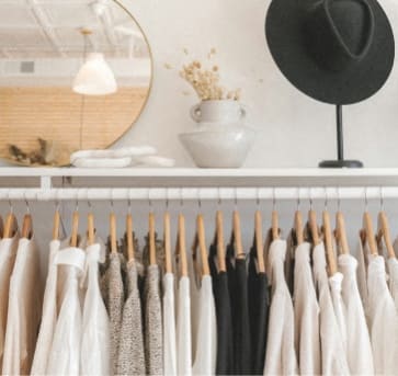a row of clothes on a rack and a hat on a shelf