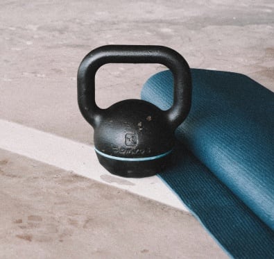 a black kettlebell with a blue resistance band on the floor