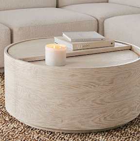 A white candle sits on a coffee table with a book on top.