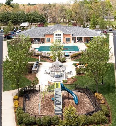 A playground with a slide and a gazebo in the middle of a grassy area at Axis at Lakeshore Apartments, Bridgewater