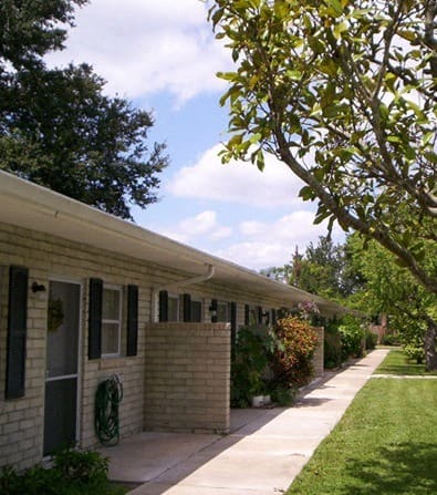 a sidewalk in front of a house with a tree