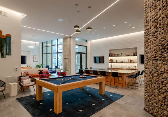 A room with a pool table and a stone pillar.