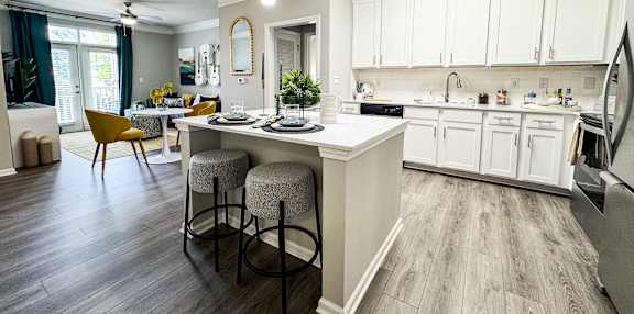 A kitchen with a white island and bar stools.