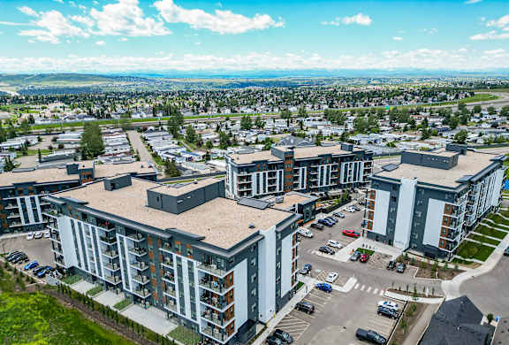 A modern apartment complex with a parking lot in front.