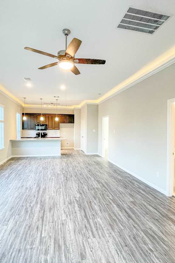 an empty living room with a kitchen in the background