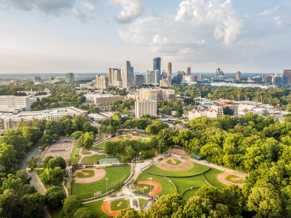 an aerial view of a park with a city skyline in the background