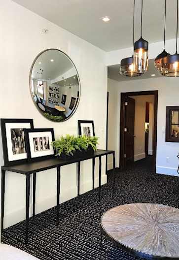 A hallway with a black and white checkered floor, a round mirror, and a table with a plant on it.