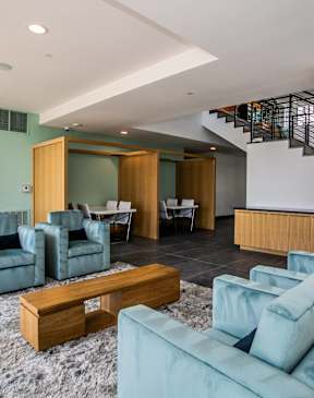 A living room with a staircase and a green couch.