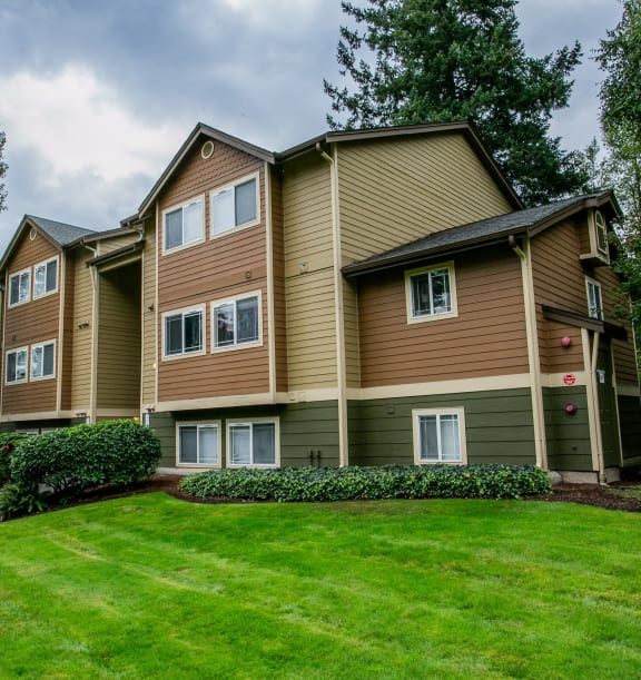 an apartment building with green grass and trees
