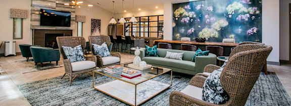 A living room with a large mural on the wall and a variety of seating options.