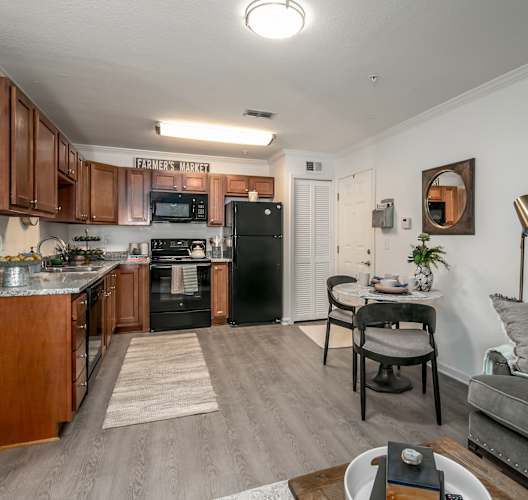 A kitchen with a black refrigerator and a grey couch.