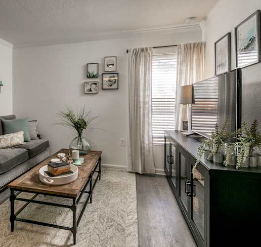 A living room with a grey couch, a coffee table, and a painting on the wall.