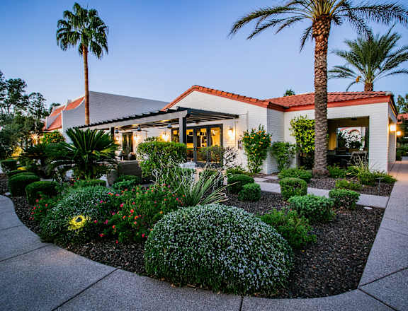 the exterior of a restaurant with palm trees and landscaping