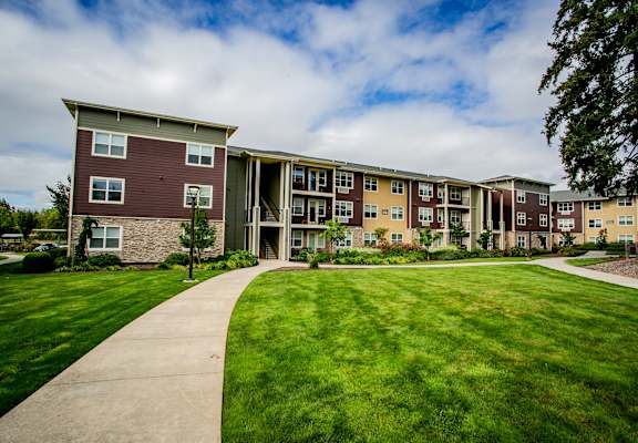 an exterior view of an apartment building with a green lawn