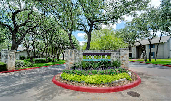 The entrance to the Polo Club is surrounded by trees and greenery. at Polo Clubs Apartments, Austin, TX 78729