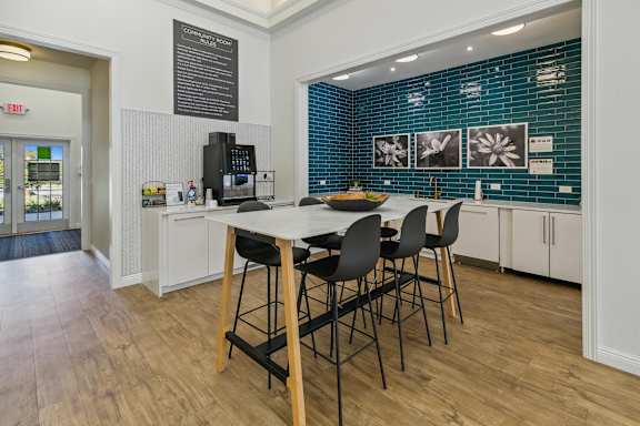 A kitchen with a table and chairs in front of a blue tiled wall.