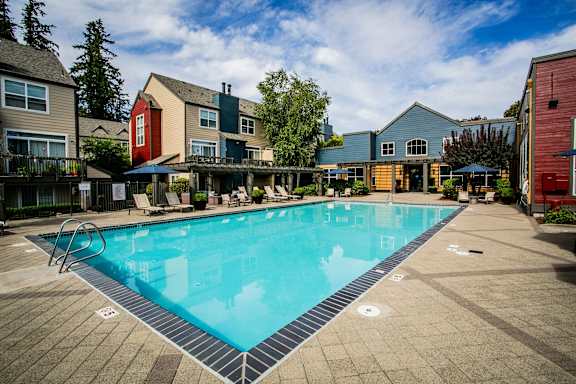 A swimming pool surrounded by a wooden deck and buildings.