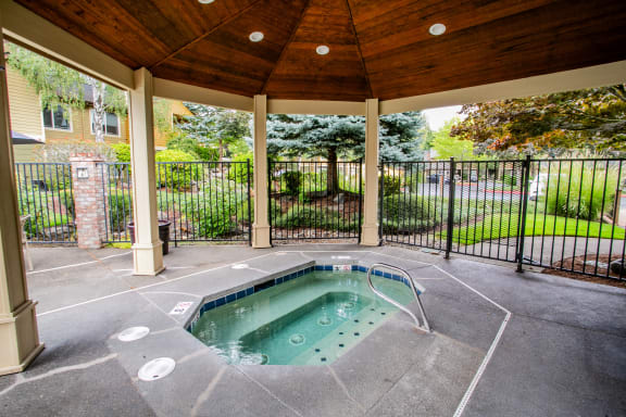 a hot tub in a patio with a fence and a house