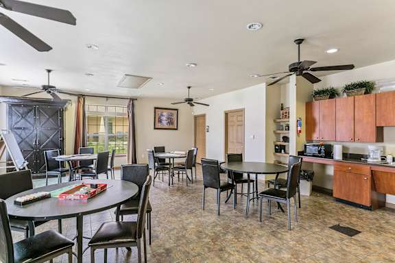A dining room with a table set for six with a black table cloth and a potted plant on the counter.
