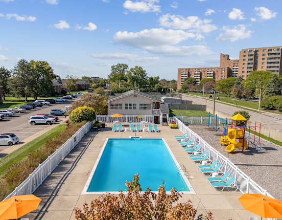A pool with chairs and a slide in the middle of a parking lot.