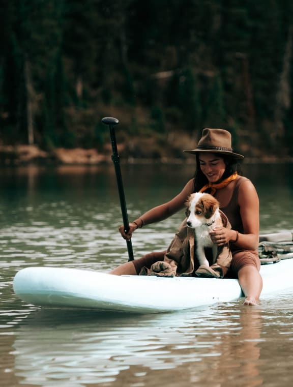 a woman and her dog on a kayak on the lake