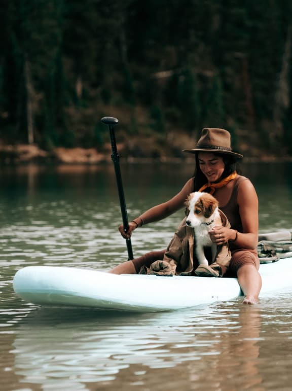 a woman and her dog on a kayak on the lake
