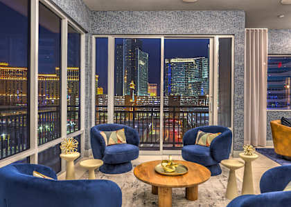 A living room with blue chairs and a view of the city at night.