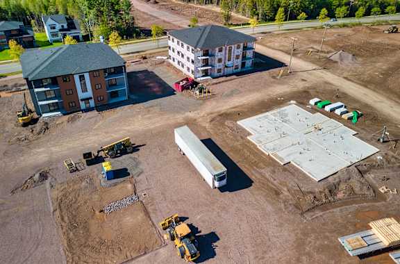 A construction site with a building under construction and construction vehicles present.