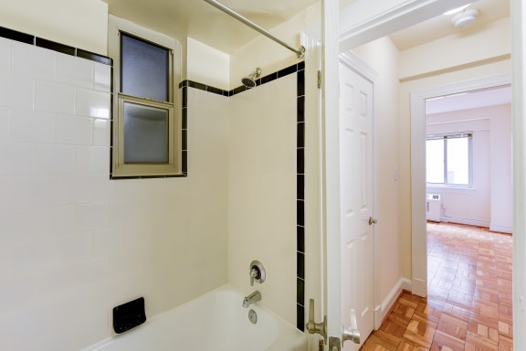 bathroom with tub, window, tile detail and view of bedroom at sherry hall apartments in washington dc