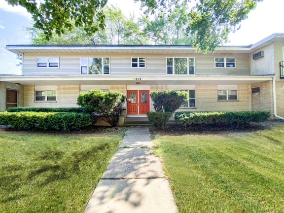 the front of a house with a walkway and a red door