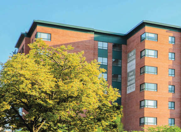 a red brick apartment building with green and yellow trees in front of it at Symphony Center Apartments, Baltimore, MD, 21201