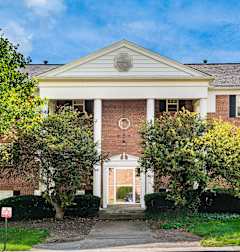 A red brick building with a white pediment and a white door.