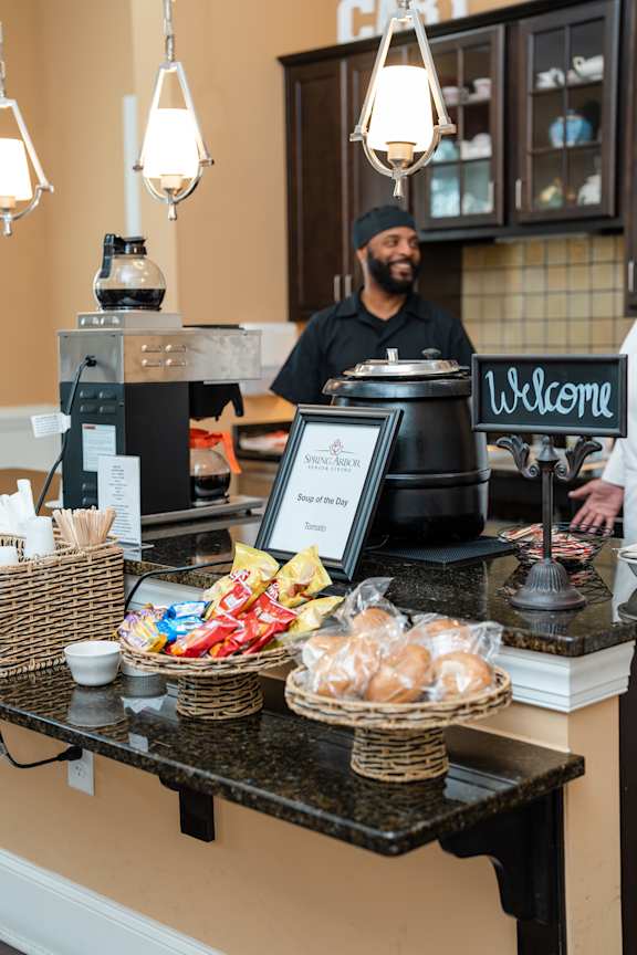 A man is standing behind a counter with a sign that says "Welcome".