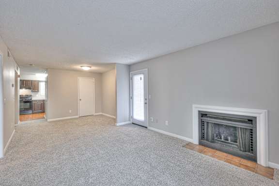 A spacious living room with a fireplace and a door leading to another room at Landmark at Lyncrest Reserve Apartments, Nashville, TN, 37209