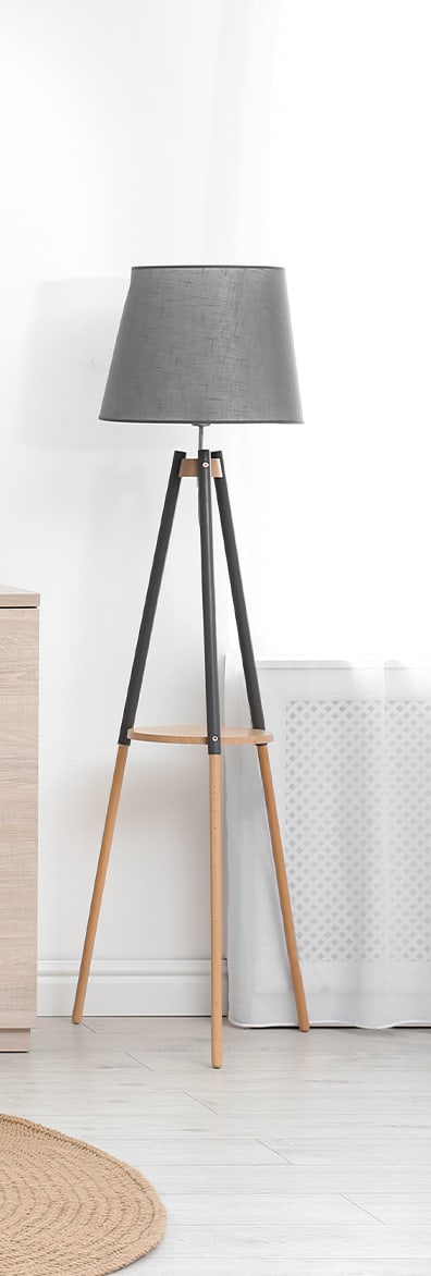 a wooden tripod floor lamp with a charcoal shade