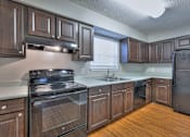 Thumbnail 6 of 28 - A kitchen with dark wood cabinets and a black refrigerator at Landmark at Lyncrest Reserve Apartments, Nashville, TN, 37209
