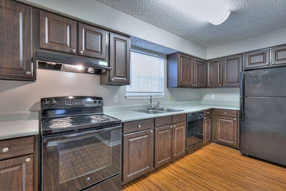 A kitchen with dark wood cabinets and a black refrigerator at Landmark at Lyncrest Reserve Apartments, Nashville, TN, 37209