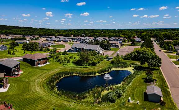 A bird's eye view of a residential area with houses and a pond.