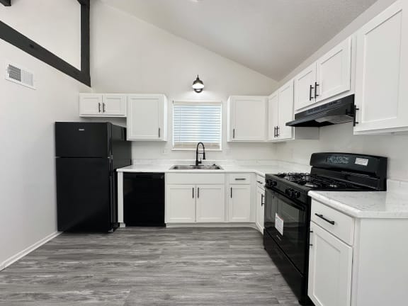 an empty kitchen with white cabinets and black appliances