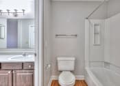 Thumbnail 13 of 28 - A white toilet in a small bathroom with a white tub at Landmark at Lyncrest Reserve Apartments, Nashville, TN, 37209