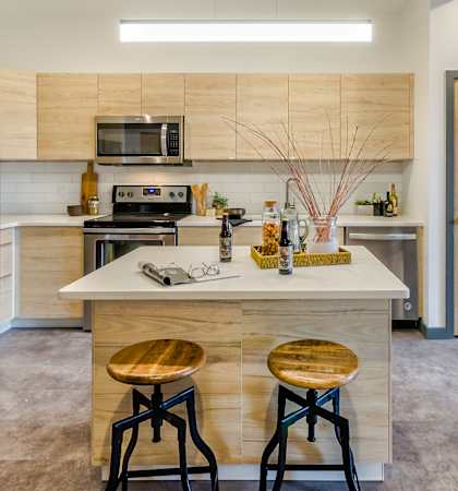 A kitchen with a refrigerator, stove, and bar stools.