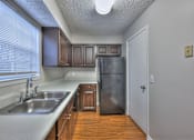 Thumbnail 7 of 28 - A kitchen with a sink, refrigerator, and wooden cabinets at Landmark at Lyncrest Reserve Apartments, Nashville, TN, 37209