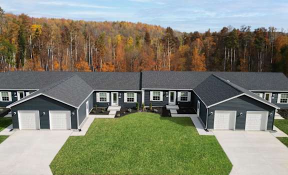 a view of a house with a lawn and a forest in the background at Hangar Flats, Batavia