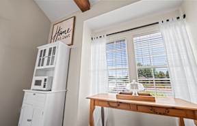 a home office with a wooden desk and a large window