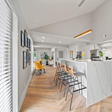 an open kitchen and living room with a bar and yellow chairs