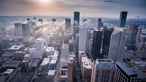 A cityscape with tall buildings and a hazy sky.