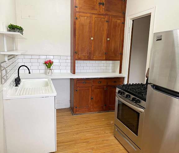 A kitchen with a stove, sink, and cabinets.