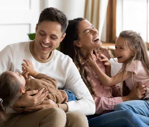 a family sits on a couch and smiles at each other