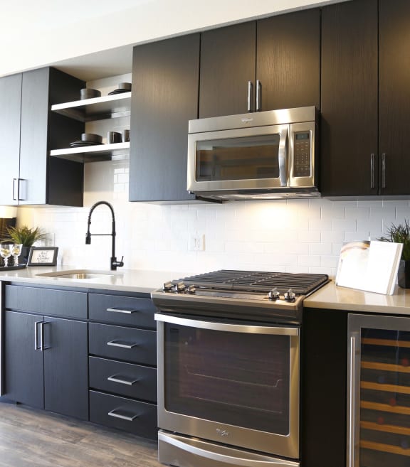 a modern kitchen with stainless steel appliances and black cabinets